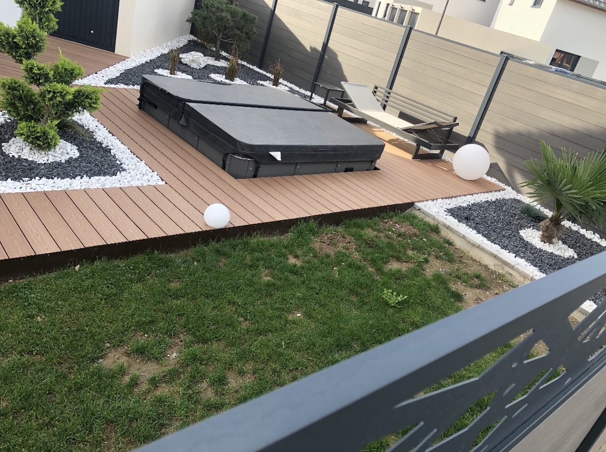 Aménagement extérieur avec terrasse composite, jacuzzi et jardin minéral par Infini Paysage