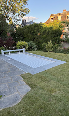 Piscine avec volet de sécurité immergé entourée d'une pelouse engazonnée